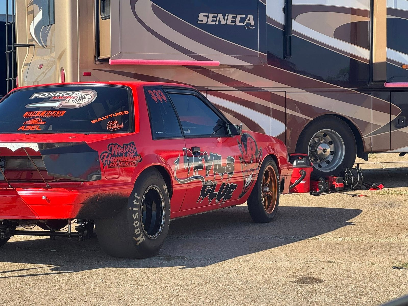 Red race car beside its transport trailer